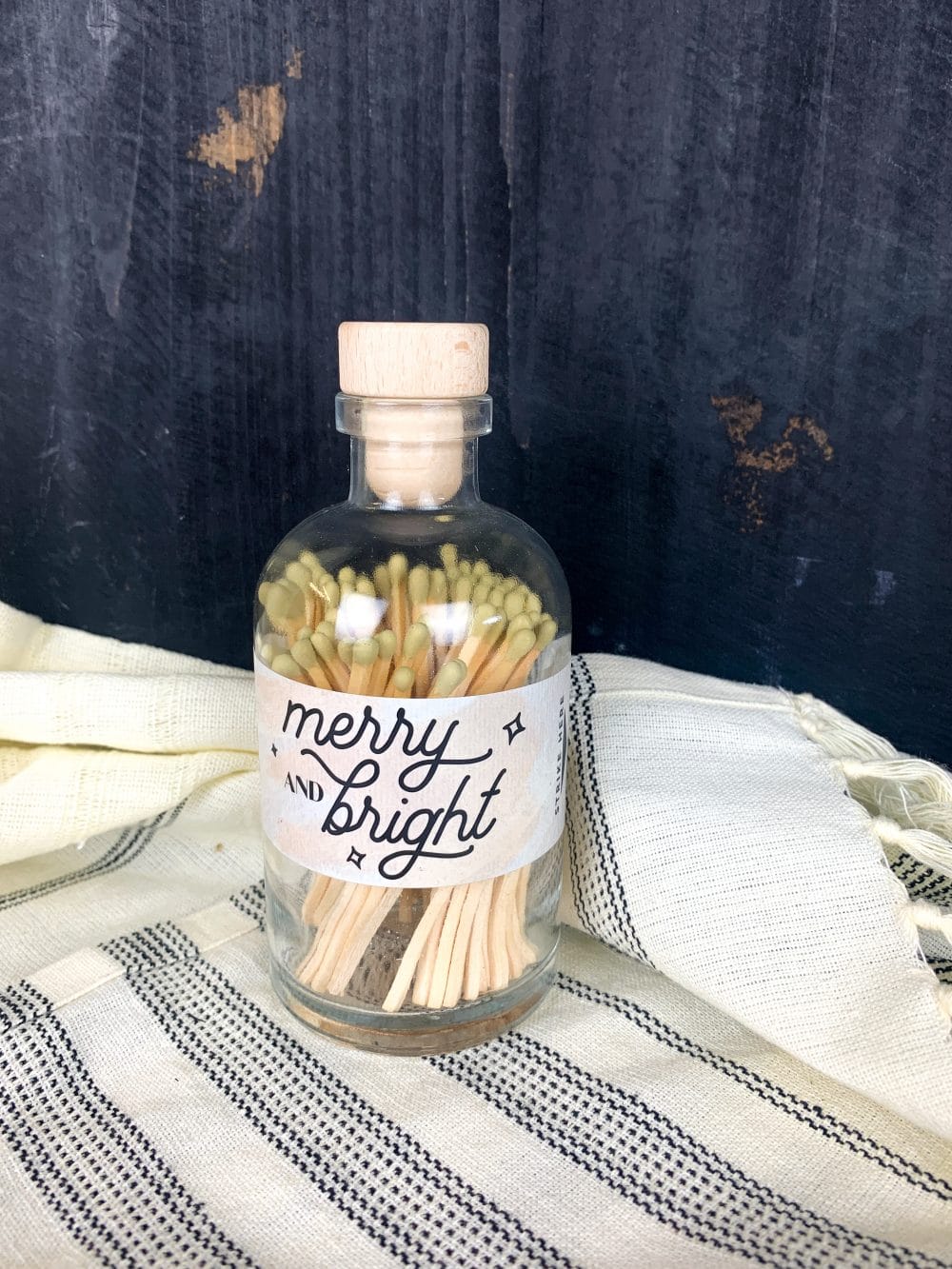 apothecary jar filled with gold-tipped matches and a “Merry and Bright” holiday label.